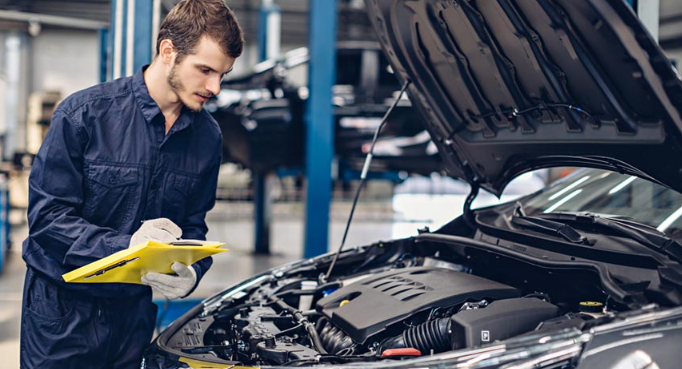 A mechanic standing in garrage to inpect the car in her workshop